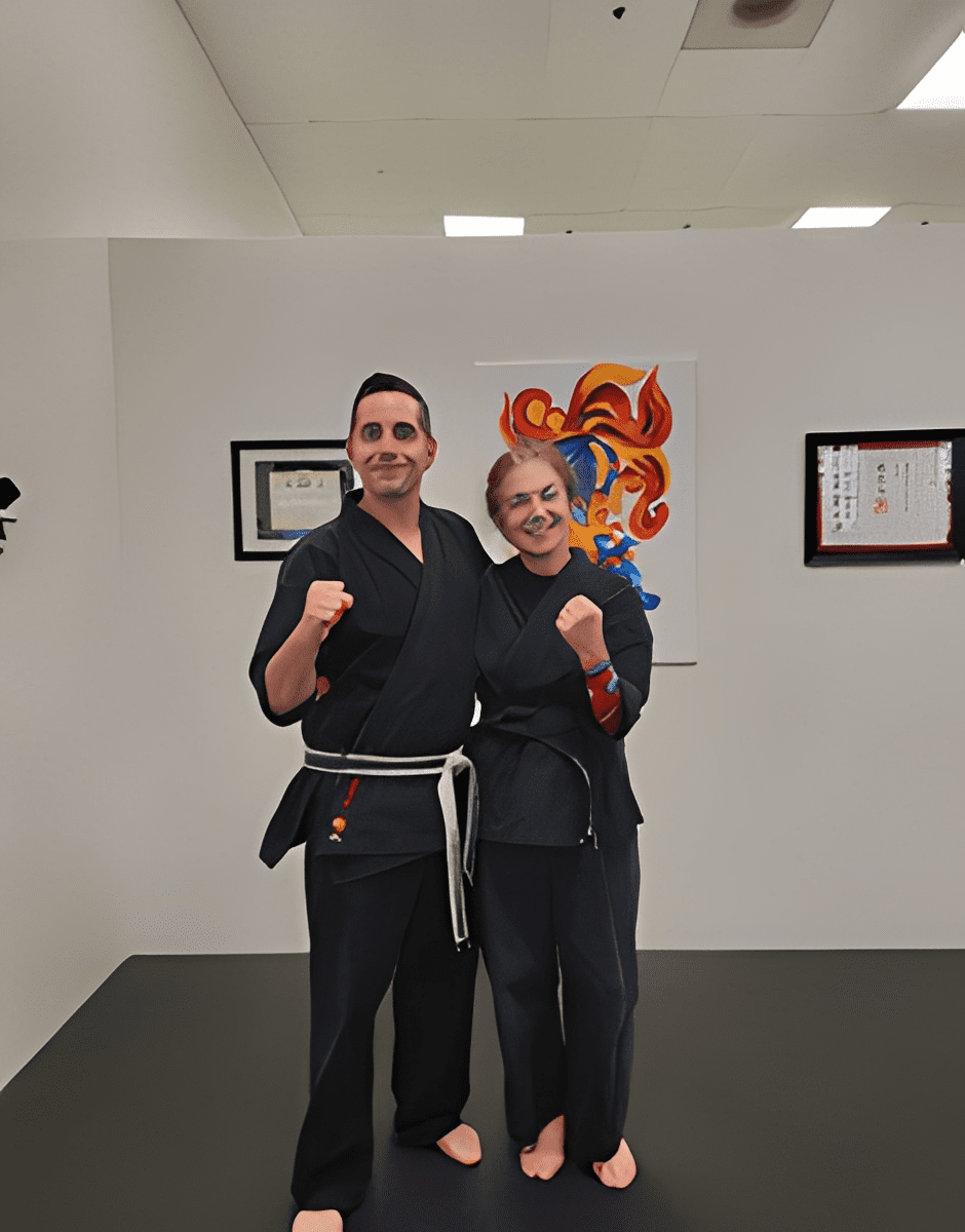 Two martial artists posing with thumbs up in a dojo.