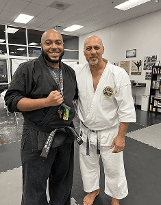 Two martial artists posing together in a dojo.